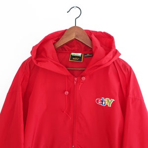 May include: Red hooded jacket with a zip fastening and the eBay logo embroidered on the front. The logo is in multi-coloured lettering.