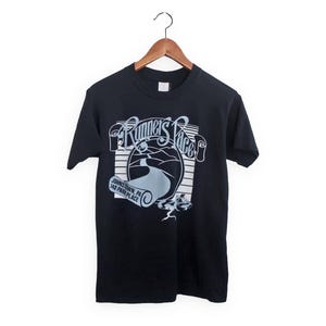 May include: Black t-shirt with a white graphic of "Runner's Place" in a retro style. The graphic includes a winding road and the text "Johnstown, PA 140 Park Place".