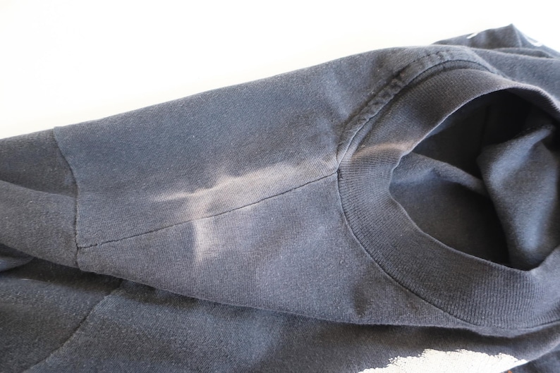 May include: A dark blue t-shirt with a faded white mark on the shoulder.