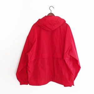 May include: A red hooded jacket with a zip fastening and a drawstring hood.