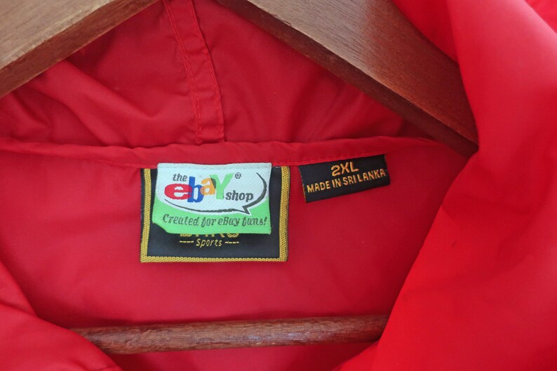 May include: Red hooded jacket with a black label that says "the ebay shop" and "Created for ebay fans!" in white text. The label also has a gold border and the text "Sports" in white text. A second black label says "2XL MADE IN SRI LANKA" in white text.