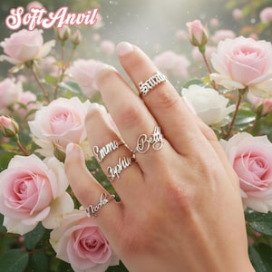 May include: A set of three ceramic mugs with a speckled, cream-colored glaze. Each mug features a different hand-painted design: a blue floral pattern, a green leaf, and a yellow sun. The mugs have a simple, rounded shape and a comfortable handle.