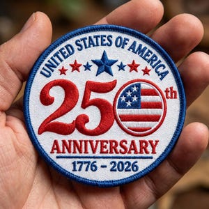 May include: A circular embroidered patch featuring the text UNITED STATES OF AMERICA, 25th ANNIVERSARY, and 1776-2026. The design includes a large red number 25, a circular American flag emblem, and blue and red stars on a white background.