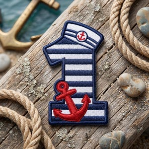 May include: A number one shaped embroidered patch featuring a navy blue and white horizontal striped pattern. The top of the number is styled like a sailor hat with a small red anchor icon, and a large red anchor is stitched at the bottom.