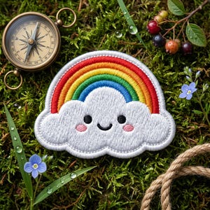 May include: A white embroidered cloud patch featuring a smiling face with black eyes, a curved mouth, and pink cheeks, topped with a vibrant red, orange, yellow, green, and blue rainbow arch, presented as a detailed fabric applique.