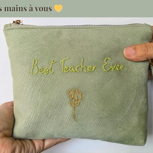 Op de afbeelding: Saliegroene etui met gouden rits en polsbandje, geborduurd met "Best Teacher Ever" in geelgroen schrift en een gouden bloem. De tekst "De nos mains &agrave; vous" staat bovenaan.