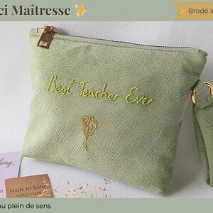 Op de afbeelding: Een lichtgroen etui met een gouden rits en polsbandje. De woorden "Best Teacher Ever" zijn groen geborduurd, samen met een bloemmotief. De tekst "Merci Ma&icirc;tresse" staat bovenaan.