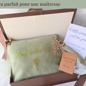 Op de afbeelding: Een geschenkdoos met een lichtgroen etui geborduurd met "Best Teacher Ever" in geel. Het etui heeft een gouden rits en een bloemmotief. De doos bevat ook een kaart met de tekst "A little something, just for you."