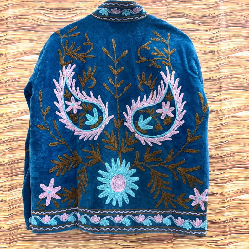K&ouml;nnte beinhalten: T&uuml;rkisfarbene Jacke mit aufwendiger Stickerei. Die R&uuml;ckseite zeigt ein gro&szlig;es Blumenmuster mit Paisley-Elementen in Rosa, Braun und T&uuml;rkis. Die Jacke hat einen hohen Kragen und einen detaillierten Besatz.