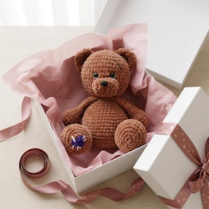 May include: A white ceramic mug with a black handle and the text "But First, Coffee" in a bold, black font. The mug is set against a blurred background, suggesting a cozy setting.