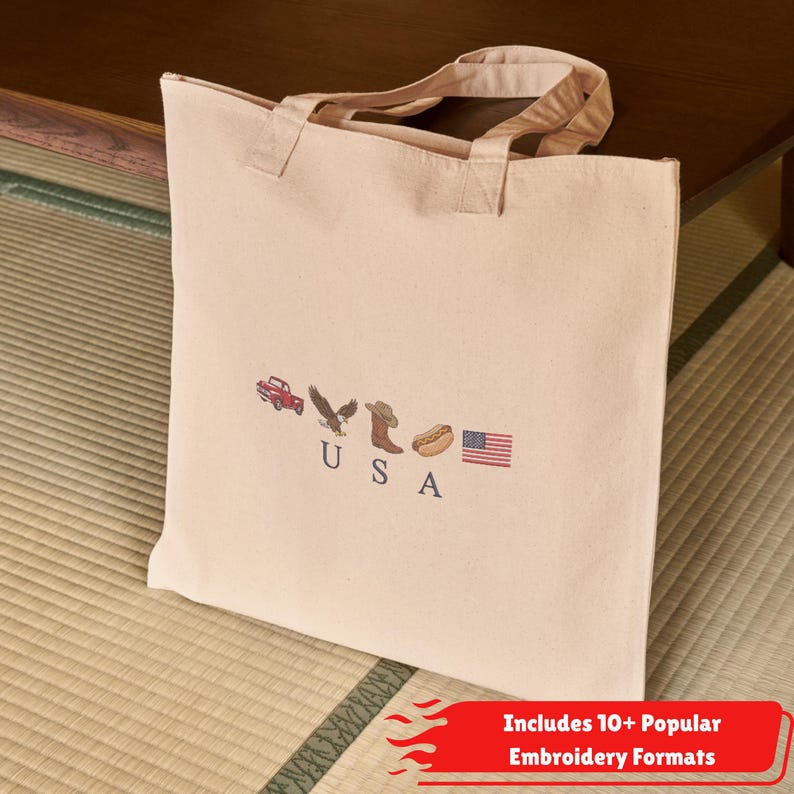 K&ouml;nnte beinhalten: Eine beigefarbene Tragetasche aus Segeltuch mit gestickten Symbolen eines roten Lastwagens, eines Adlers, eines Cowboystiefels, eines Hotdogs und der amerikanischen Flagge sowie den dunkelblau gestickten Buchstaben U S A.