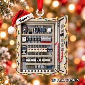 Puede incluir: Un adorno rectangular de panel de control eléctrico con un gorro de Papá Noel rojo que tiene el nombre Henry impreso en el borde blanco. El panel está decorado con una cadena de luces navideñas multicolores y tiene una puerta abierta.