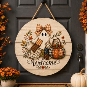 May include: A round wooden door sign with a light wood grain finish featuring a ghost illustration wearing a plaid bow, holding a patterned pumpkin basket, and the word Welcome in black script, suspended by a thick jute rope cord.