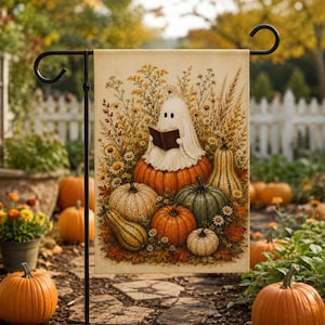 May include: A rectangular garden flag featuring a white ghost sitting on a large orange pumpkin while reading a brown book. The scene includes various pumpkins, gourds, and autumn wildflowers in shades of orange, yellow, and green on a cream background.
