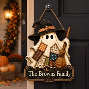 May include: A decorative hanging sign featuring a ghost wearing a black witch hat with an orange band. The ghost has a patchwork body with various patterns and holds a wooden broom. Below, a dark plaque displays the text The Browns Family.