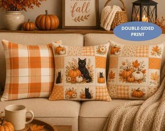 May include: Three square throw pillows featuring a patchwork design with orange and white plaid patterns, illustrations of black cats, pumpkins, and autumn leaves. The pillows are displayed on a beige sofa with a textured throw blanket nearby.
