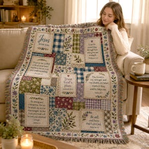 May include: A woven throw blanket featuring a patchwork design of floral patterns, blue and white gingham, and cream-colored panels. The panels contain religious text including Jesus loves you, Trust in the LORD, and Be still, and know I am God.