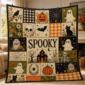 May include: A patchwork quilt featuring Halloween motifs including ghosts, pumpkins, a skull, a black cat, a spider web, and a haunted house. The central panel displays the word SPOOKY in black lettering against a cream background with stars.