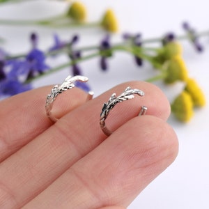 May include: A pair of silver hoop earrings with a delicate branch design. The earrings are small and dainty, perfect for everyday wear.