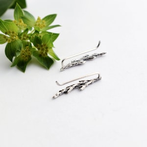 Puede incluir: Un par de pendientes de plata con un delicado dise&ntilde;o de rama. Los pendientes est&aacute;n hechos de metal fino y tienen un acabado ligeramente oxidado.