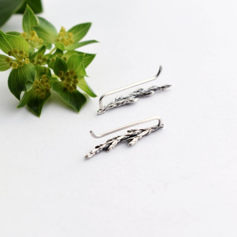 Puede incluir: Un par de pendientes de plata con un delicado dise&ntilde;o de rama. Los pendientes est&aacute;n hechos de metal fino y tienen un acabado ligeramente oxidado.