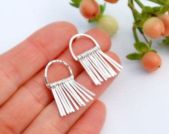 Puede incluir: Un par de pendientes de plata con un diseño de flecos. Cada pendiente tiene un pequeño aro con una serie de barras finas de plata que cuelgan.