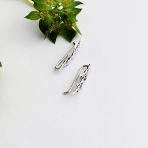 Puede incluir: Un par de pendientes de plata con un delicado dise&ntilde;o de hojas. Los pendientes est&aacute;n hechos de metal y tienen un aspecto simple y elegante.