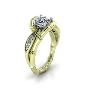 May include: A yellow gold ring featuring a bamboo-inspired band design. The setting holds a single round brilliant-cut centre stone in a white metal prong setting, accented by three small round stones embedded along one side of the bamboo stalk.
