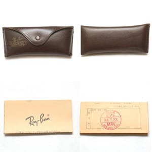 May include: A collection of Ray-Ban accessories, including a brown leather case with a button closure and the text "Ray-Ban TRADITIONALS". Also included is a tan box with the Ray-Ban logo and a small card.