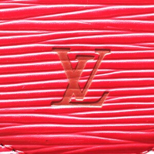 May include: A bright red leather surface featuring a distinct horizontal wavy texture and a debossed Louis Vuitton logo centered in the middle. The material displays a consistent grain pattern with deep grooves running across the entire frame.