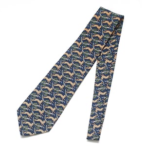 Puede incluir: Corbata azul marino con un estampado repetido de guepardos corriendo en beige y verde. La corbata está hecha de una tela suave, adecuada para vestimenta formal o de negocios.
