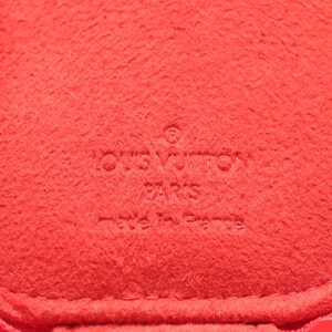 May include: A bright red textured material featuring an embossed logo that reads LOUIS VUITTON PARIS made in France. The surface has a soft, felt-like appearance with a consistent vibrant red color throughout the entire visible area of the item.