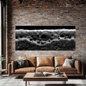 Puede incluir: Una impresión artística abstracta en blanco y negro que presenta un primer plano de burbujas. La obra de arte se exhibe sobre un sofá de cuero marrón y una mesa de centro de madera en una habitación con una pared de ladrillo.