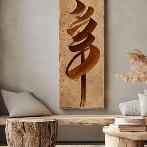 May include: A rectangular artwork featuring abstract brown calligraphy on a textured, beige background. The artwork is mounted on a wooden frame and hangs on a neutral-colored wall. The overall aesthetic is minimalist and artistic.