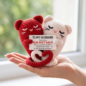 May include: Two crocheted cat figures, one red and one white, holding a rectangular card that reads: TO MY HUSBAND You're my PUR-FECT HALF! You're my favorite face, my favorite smile, & my favorite purrrson! Their tails are intertwined in a heart shape.