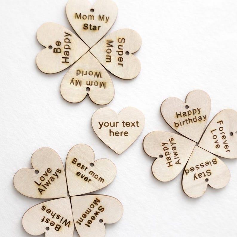 May include: Wooden heart-shaped ornaments with engraved messages. Some are arranged in four-leaf clover shapes, with phrases like "Mom My Star" and "Happy Birthday." One heart reads "your text here."