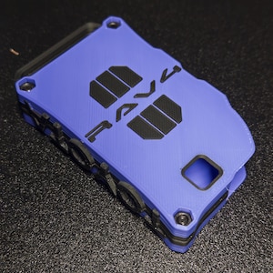 May include: A rectangular blue and black wallet with a layered, 3D-printed texture. The front features the word "RAVE" in bold black lettering, with two black rectangular accents. It includes a small square cutout and visible black screw heads.