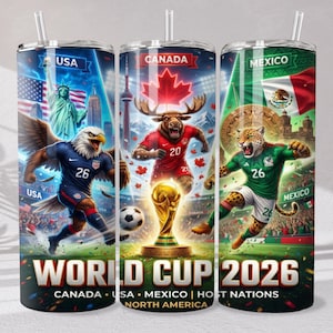 May include: Three cylindrical tumblers with straws featuring World Cup 2026 graphics. The designs display the USA with a bald eagle and Statue of Liberty, Canada with a moose and maple leaf, and Mexico with a jaguar, all in soccer uniforms.