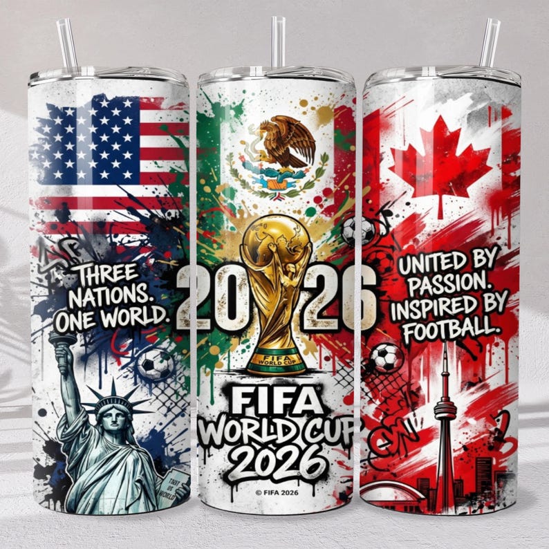 May include: Three cylindrical tumblers with straws featuring FIFA World Cup 2026 graphics. Designs include the US, Mexican, and Canadian flags, the Statue of Liberty, the CN Tower, a gold trophy, soccer balls, and text reading Three Nations One World.