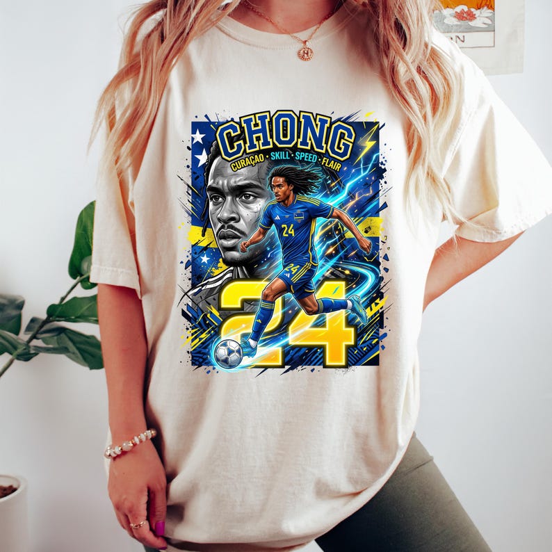 May include: Cream-colored t-shirt featuring a graphic of a soccer player with the name "CHONG" above. The design includes the words "CURACAO SKILL SPEED FLAIR" and the number "24". The player is depicted in blue and yellow.
