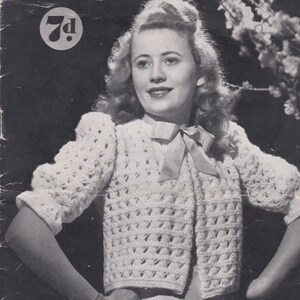May include: A vintage black and white image of a woman wearing a white knitted cardigan. The image is from a "Sun-glo Knitting Book" with the text "Series 71" and "Design No. 2933". The woman is smiling and has her hands on her hips.