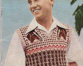 Pode incluir: Uma capa de livro de tricô vintage com um homem vestindo um colete de tricô marrom e branco com uma camisa branca. A capa é azul com o texto "Patons Knitting Book" em vermelho e branco. O número do livro é "R.14" e o preço é "1/9d."