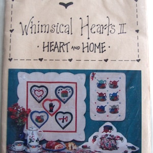 May include: A craft pattern book titled "Whimsical Hearts II: Heart and Home" by Jupiter. The cover features a quilt with hearts and a teapot design.