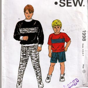 May include: Kwik Sew pattern 1998 for children's clothing. The pattern features illustrations of two outfits: a black and white striped sweater and trousers, and a red and blue striped shirt and shorts. Sizes 4-5-6-7.