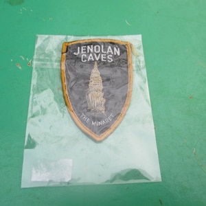 May include: A black and gold embroidered patch with the text "Jenolan Caves" and "The Minaret".