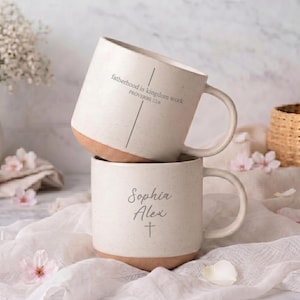 May include: Two stacked white ceramic mugs with brown bottoms. The top mug has the text "fatherhood is kingdom work PROVERBS 22:6". The bottom mug has the name "Sophia Alex" and a cross symbol.