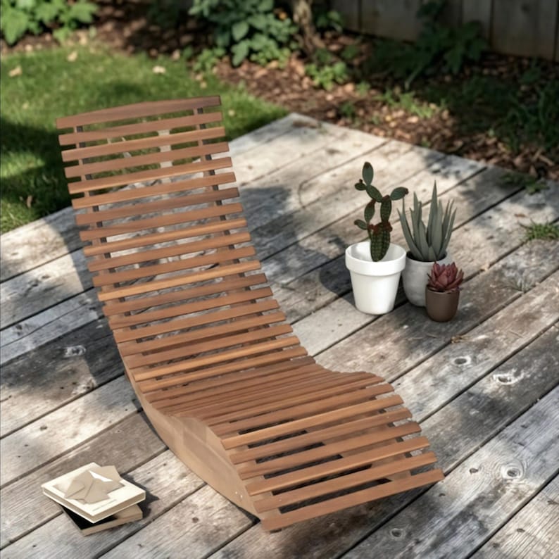 Op de afbeelding: Een houten ligstoel voor buiten met een lattenontwerp. De stoel is gemaakt van lichtbruin hout en is gebogen voor comfort. De stoel staat op een houten terras, met potplanten in de buurt.