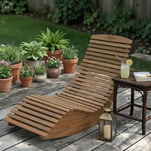 Op de afbeelding: Een houten chaise longue met latten, ideaal voor buiten, omringd door potplanten. Een kleine bijzettafel bevat een drankje met een schijfje citroen en een boek. Een verlichte lantaarn draagt bij aan de sfeer.