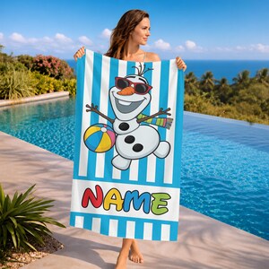 K&ouml;nnte beinhalten: Blau-wei&szlig; gestreiftes Strandtuch mit einem Cartoon-Schneemann, der eine Sonnenbrille tr&auml;gt und einen Strandball h&auml;lt. Das Handtuch hat das Wort "NAME" in bunten Buchstaben am unteren Rand. Ideal f&uuml;r einen Tag am Strand oder am Pool.