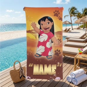 May include: A beach towel featuring a cartoon character in a red dress with white leaf patterns, set against a sunset scene with paw prints. The towel has the word "NAME" in gold letters at the bottom. A straw bag and rolled towels are in the foreground.